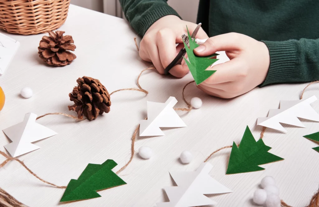 Enfant fabriquant une décoration de Noël éco-responsable avec du papier et des ciseaux