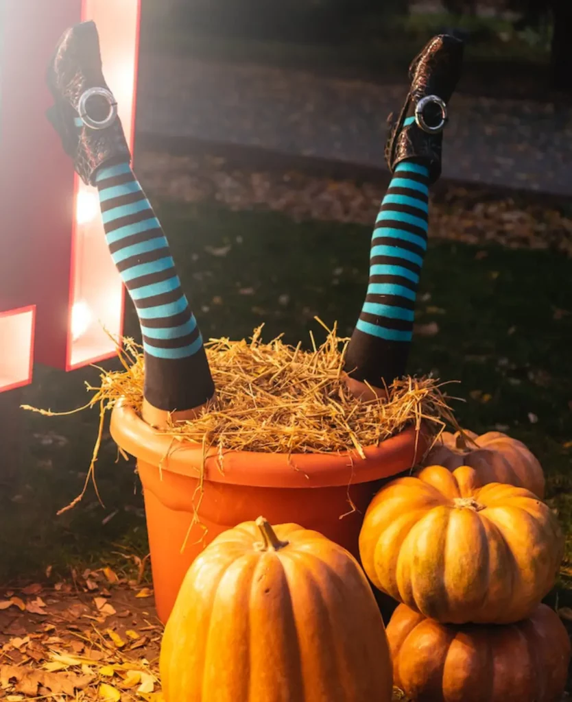 Déco d'Halloween fausses jambes sortant d'un pot de fleurs avec des citrouilles