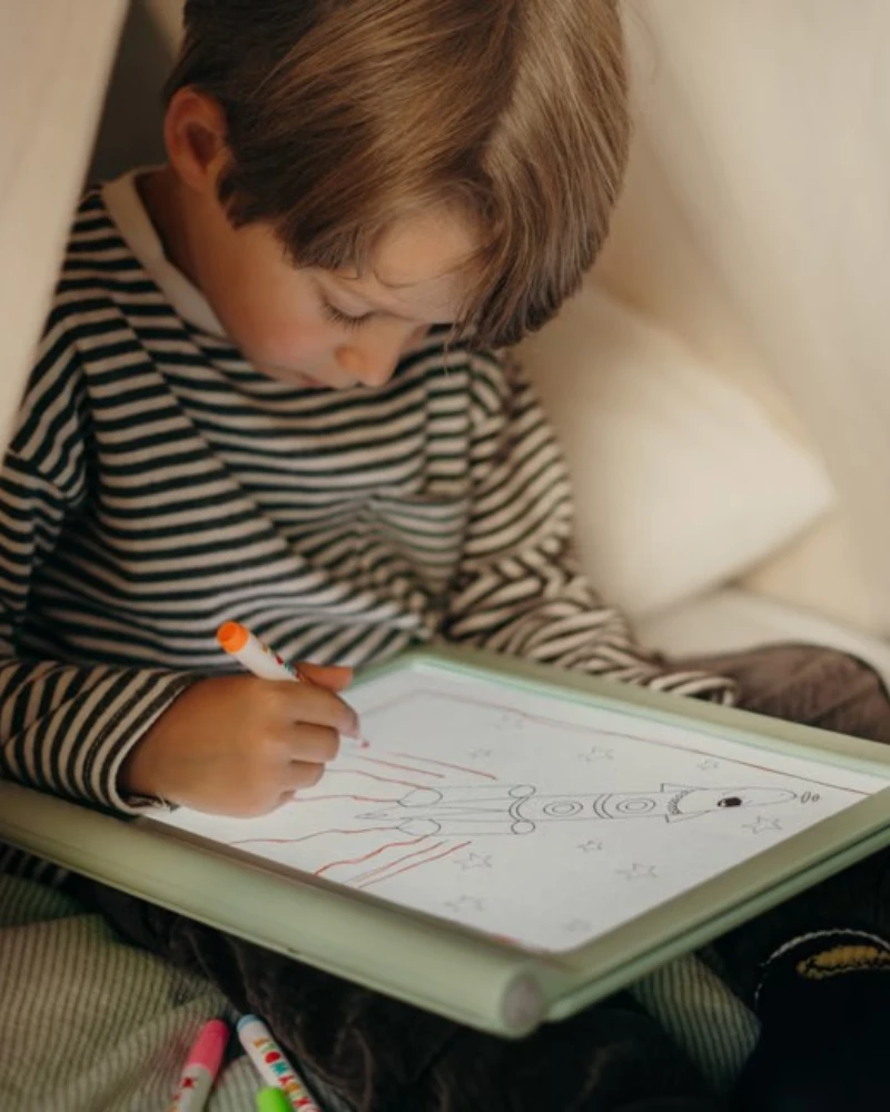 Enfant dessinant sur sa tablette lumineuse Kidydraw reçue en cadeau à Noël